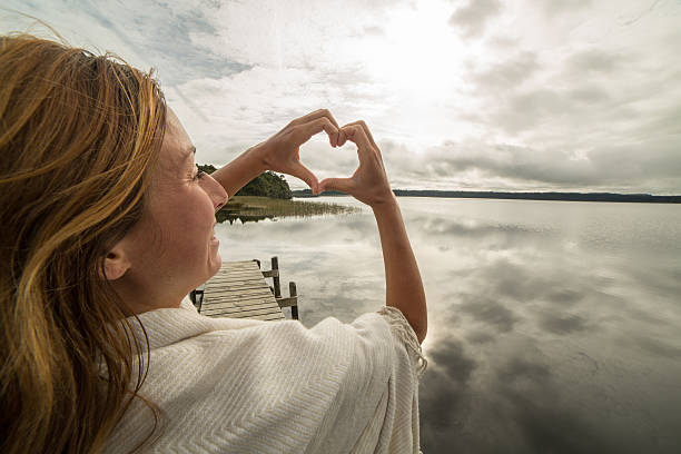 istock Woman frames mountain lake landscape into heart shape 545678118