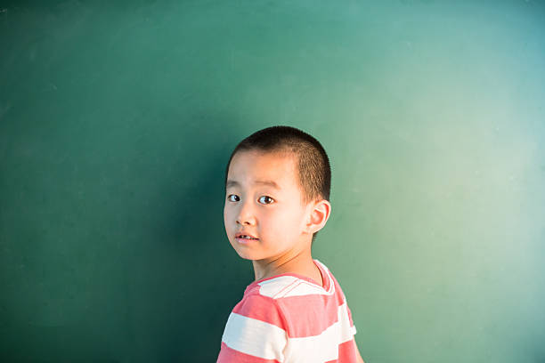 istock asian boy standing infront of chalkboard 545681602