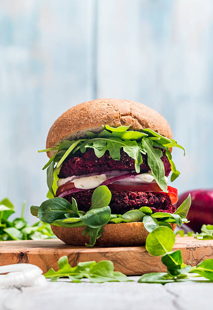 Vegetarian burger made of beetroot Vegetarian burger made of beetroot, tomato, corn salad and arugula on wooden background veggie burger photos stock pictures, royalty-free photos & images