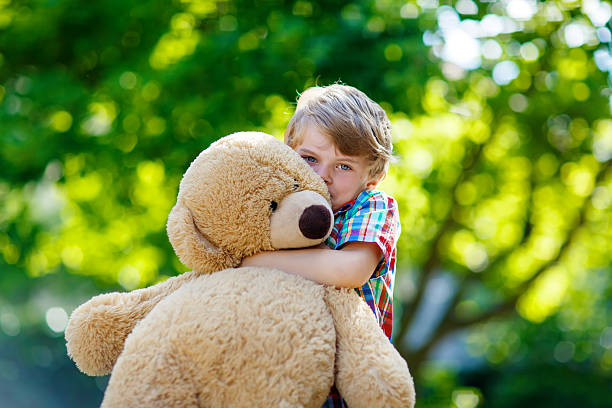 istock Little kid boy playing with big plush bear, outdoors. 545774798