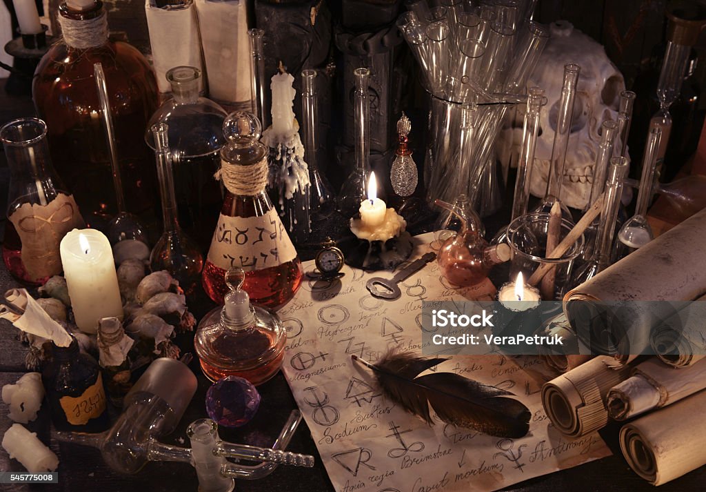 Mystic still life with alchemy paper, bottles and candles Mystic still life with old parchments papers, vintage bottles, candles, skull and magic objects. Ancient pharmacy, medieval alchemist or witch laboratory, ritual with occult and esoteric symbols The Past Stock Photo