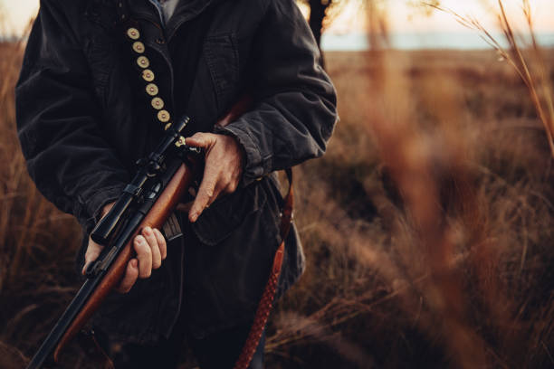 uomo che trasportava cecchino e cartuccia nel deserto - rifle hunting gun aiming foto e immagini stock