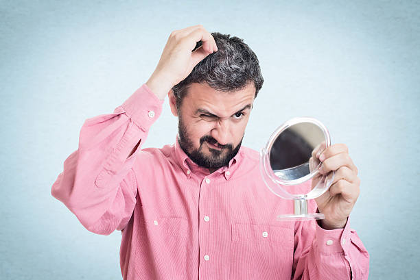 homme regardant dans le miroir au premier gris cheveux - cheveux blancs photos et images de collection