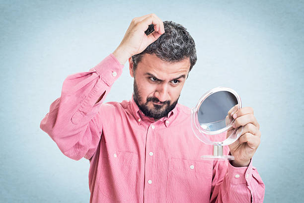 istock Man worried about gray hair looking in a mirror 545776664