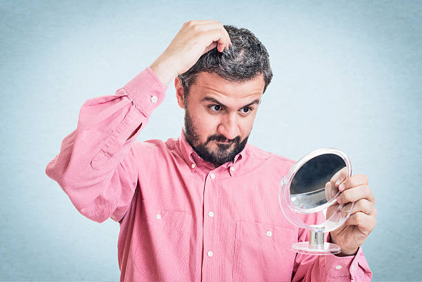 istock Man worried about gray hair looking in a mirror 545776812