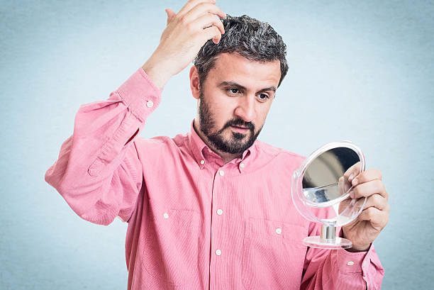 istock Man worried about gray hair looking in a mirror 545776898