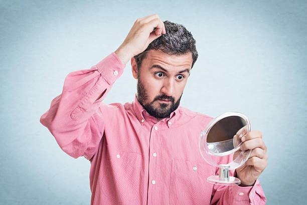 istock Man worried about gray hair looking in a mirror 545776974
