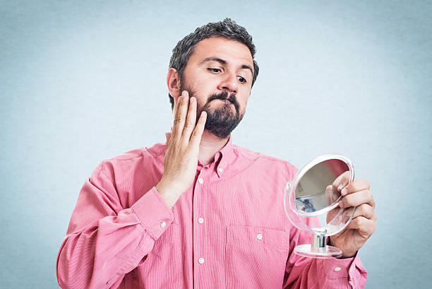 istock Young man checking his face skin and touching his beard 545777040