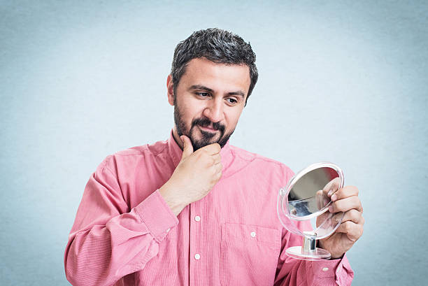 istock Man worried about gray hair looking in a mirror 545777122