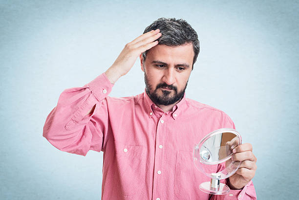 istock Man worried about gray hair looking in a mirror 545777228