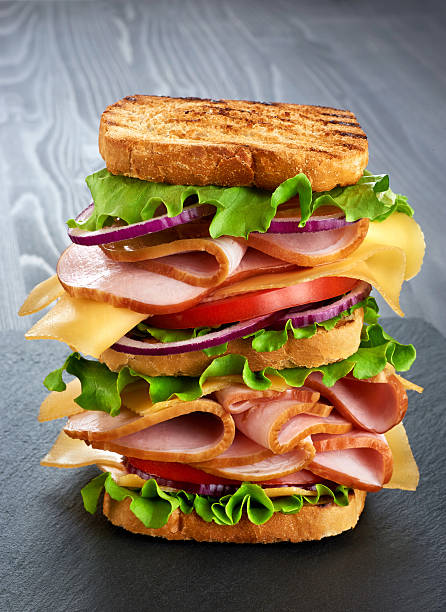 istock Big sandwich with ham and vegetables on dark wood background 545778000