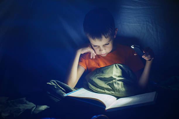 istock boy reading in the tent at night 545779212