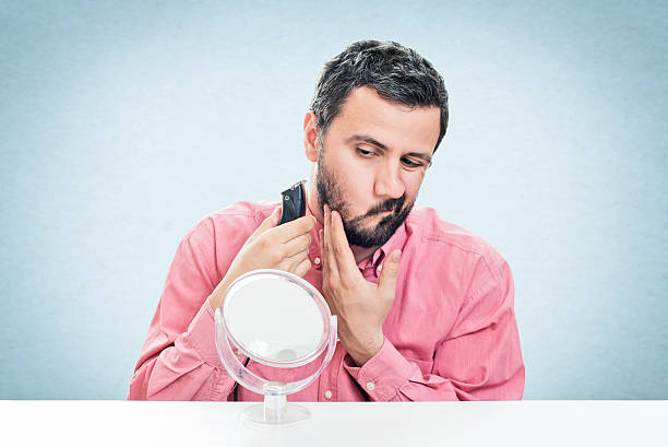 istock Young man shaving with electric razor 545779592