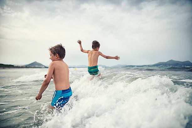 Group of happy children enjoying summer vacation, splashing water in ocean