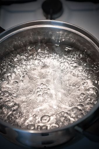 Boiling Water in a Stainless Steel Pot on a gas stove. Domestic kitchen, food preparation.