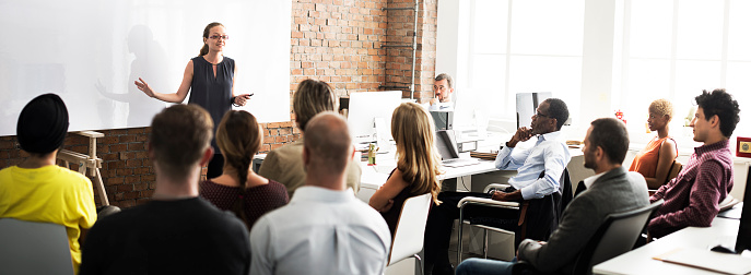 Group of people sitting on a seminar. They have their hand raised.