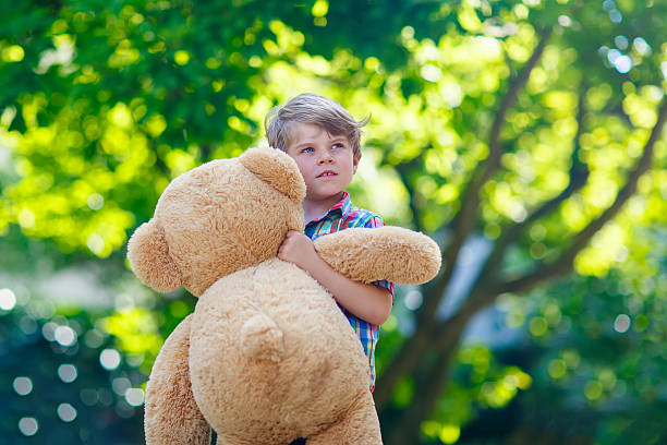 istock Little kid boy playing with big plush bear, outdoors. 545784696