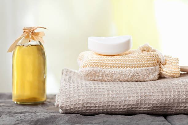 Close-up of pile of white folded towels and personal care products on bed - Selective focus, copy space for text - Concepts and ideas, personal care, luxurious lifestyle