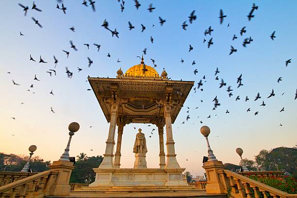 MORNING WITH PIGEONS This scene can be witnessed every morning at the gate side of Mysore palace, Thousands of pigeons flock here everyday. It is even more beautiful to see the bird lovers gathering here to feed the pigeons. The Amba Vilasa Palace – Mysore. Karnataka. karnataka stock pictures, royalty-free photos & images
