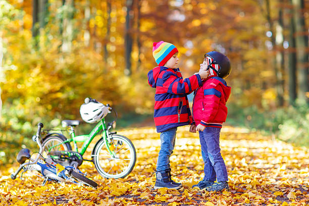 zwei kleine kinder jungen mit fahrrädern im herbstpark - safe ride stock-fotos und bilder