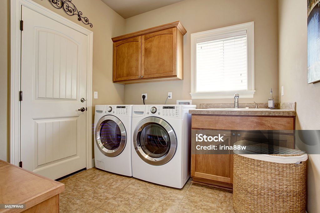 Laundry room with washer and dryer. Laundry room with washer and dryer. Wooden cabinets and tile floor Utility Room Stock Photo