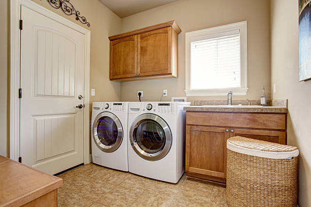 Laundry room with washer and dryer. Laundry room with washer and dryer. Wooden cabinets and tile floor utility room stock pictures, royalty-free photos & images