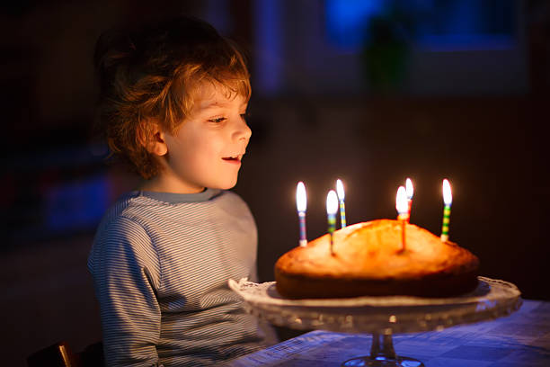 istock Little kid boy blowing candles on birthday cake 545791748