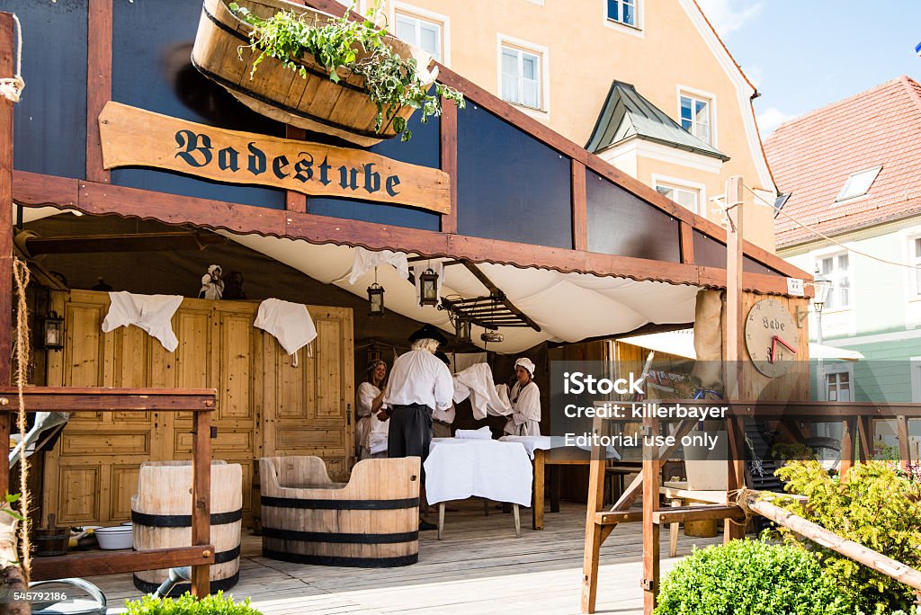 Historic Bathhouse Preparation Friedberg, Germany - July 09, 2016: Men and Women dressed in traditional costume are preparing the bathhouse in the traditional way of the eighteenth century on the historic festival Friedberger Zeit (Time of Friedberg) in Friedberg, Germany. The Festival is happening every 3 years all around this Bavarian medieval city, celebrating the time between 1680 and 1790 by its inhabitants wearing historic costumes, stalls demonstrating the craftsmanship of this period and selling authentic food and drinks. Adult Stock Photo