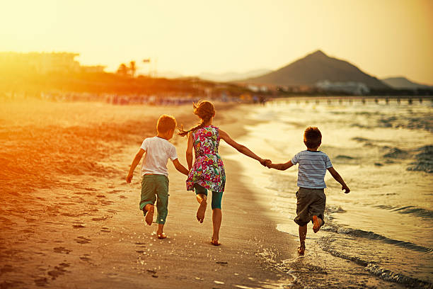 istock Brothers and sister running on beach on sunset 545794740