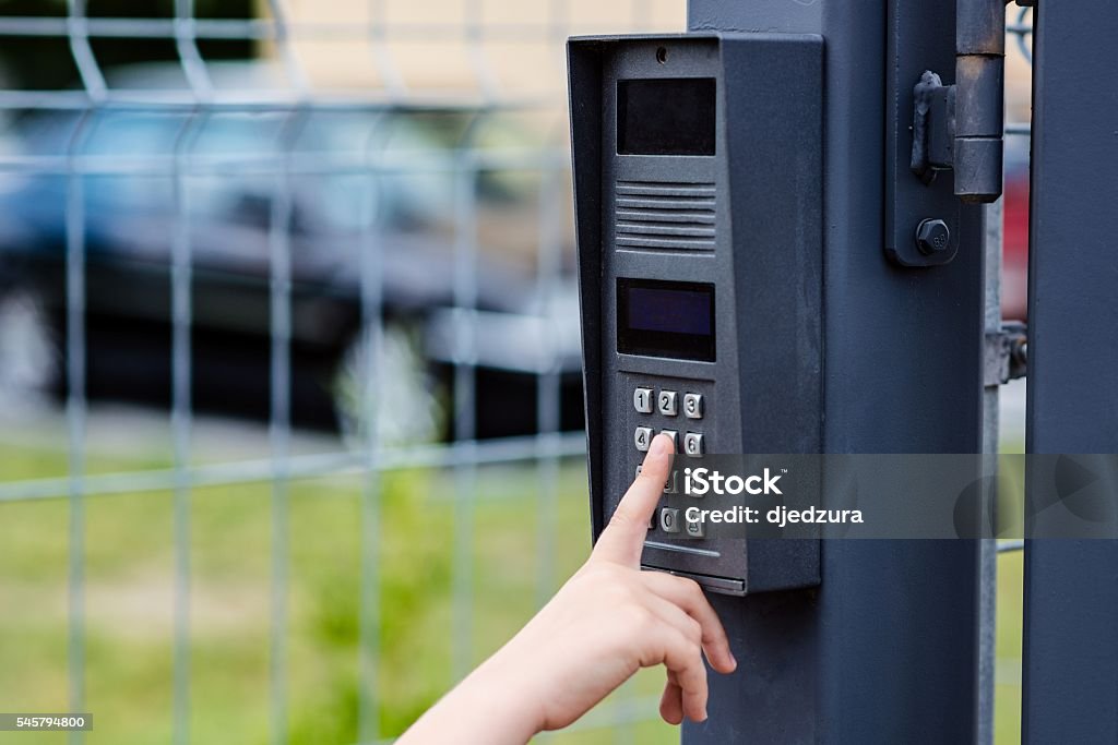 Little child boy pushes a button on the intercom Little child boy pushes a button on the intercom mounted on the gate Gate Stock Photo