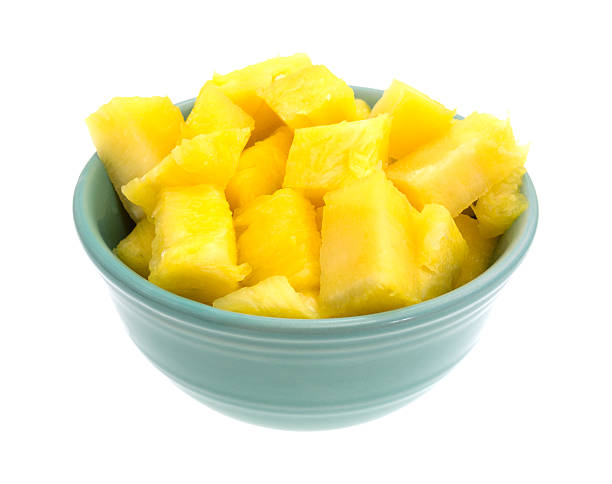 A bowl filled with freshly cut pineapple isolated on a white background.