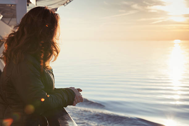 une jeune femme se tient sur le pont d’un bateau de croisière - passenger ship flash photos et images de collection