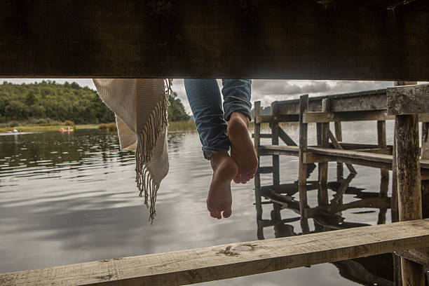 istock Woman's feet dangle from lake pier 545798908