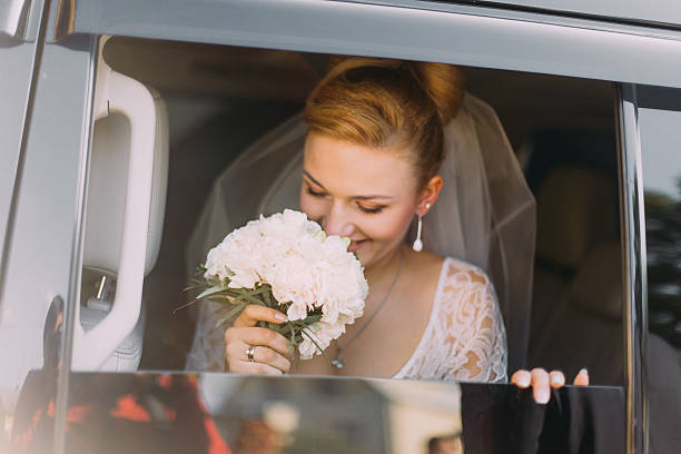 istock Happy beautiful blonde bride sniffs flowers in the car 545799328
