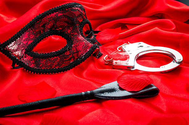 concept bdsm : recadrage, menottes et masque oculaire sur satin rouge - sensuality sexual activity desire touching photos et images de collection