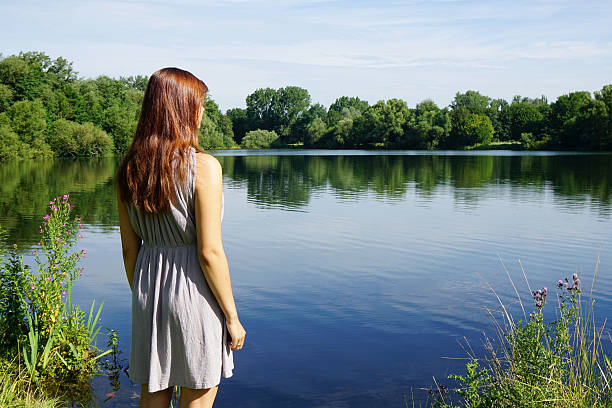 rear view of young woman looking over idyllic lake with copy space