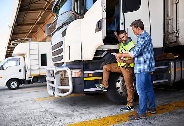 Checking the manifest one last time Shot of two coworkers talking together next to a large truck outside of a distribution center commercial land vehicle photos stock pictures, royalty-free photos & images