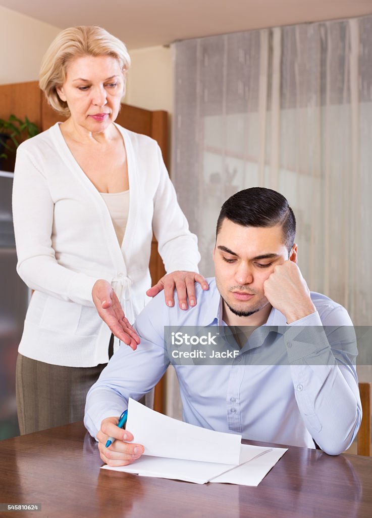 Elderly woman and young man with bills Senior woman questioning young man about letters from bank at home Adult Offspring Stock Photo