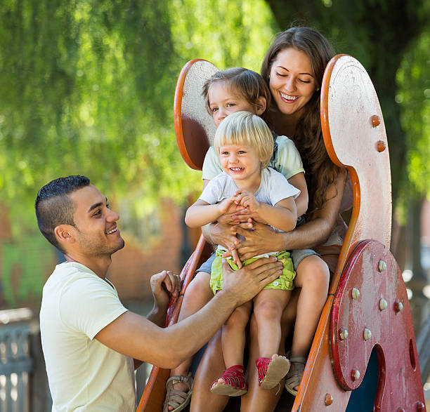istock Smiling parents helping kids on slide 545814536