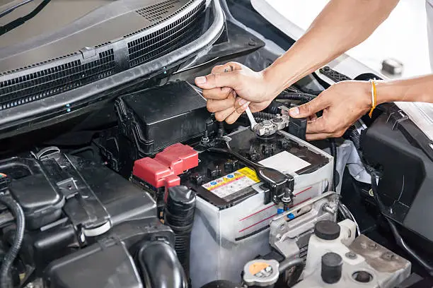 Photo of Mechanic engineer fixing car battery in garage