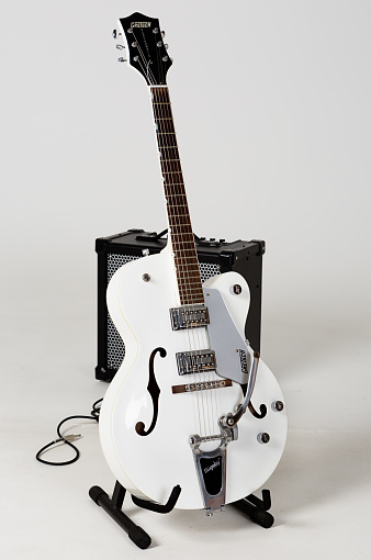 Cape Town, South Africa- July 6, 2016:  A Gretsch G5120 Electromatic archtop electric guitar with a Bigsby tremolo system, noted for its twanginess. Gretsch, an American family-owned business, was founded in 1883. It became a famous brand during the early rock 'n roll era of the mid-20th-century, with Bo Diddley and Chuck Berry prominent players. Country guitarists such as Chet Atkins, and pop artists such as George Harrison of the Beatles, also helped promote the brand. Rockabilly revivalists such as Brian Setzer and the Stray Cats have kept Gretsches familiar to modern audiences. The guitar is on a stand in front of A Roland Cube 80GX amplifier.