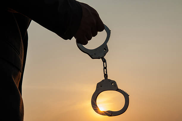 Business Man holding handcuffs after releasing over sunset background Business Man holding handcuffs after releasing over sunset background. Freedom and Burden-free concept judgement free stock pictures, royalty-free photos & images