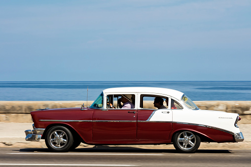 Havana, Сuba - April 16, 2016: Vintage American car speeding along the Malecon in Havana, Cuba, motion blur, Caribbean Sea is visible in the background, 50 megapixel image.