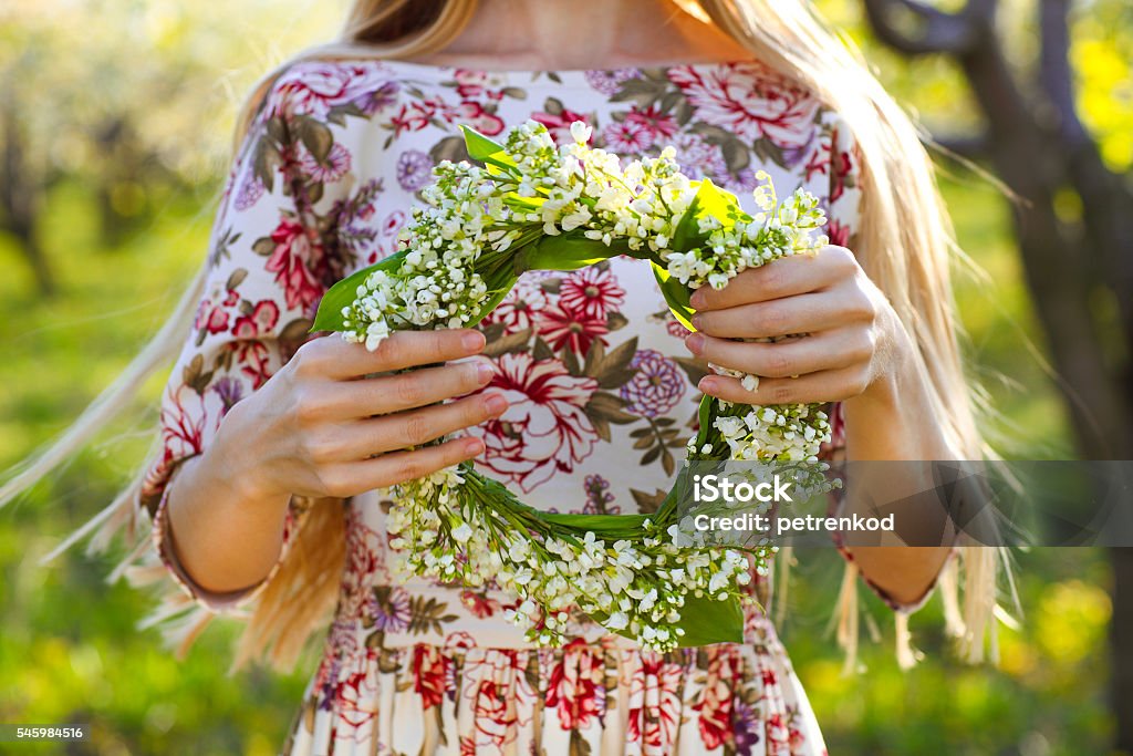 Young woman holding wreath from lily of the valley Young woman holding wreath from lily of the valley in her hands. Close up Lily-of-the-valley Stock Photo