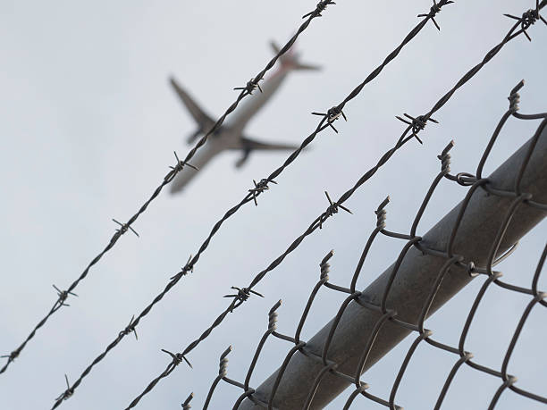 istock defoused  airplane flies behind barb wire net 545986868