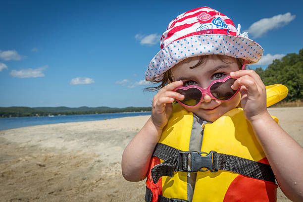 bambino che indossa un giubbotto di salvataggio giallo sulla spiaggia estiva - arm band foto e immagini stock