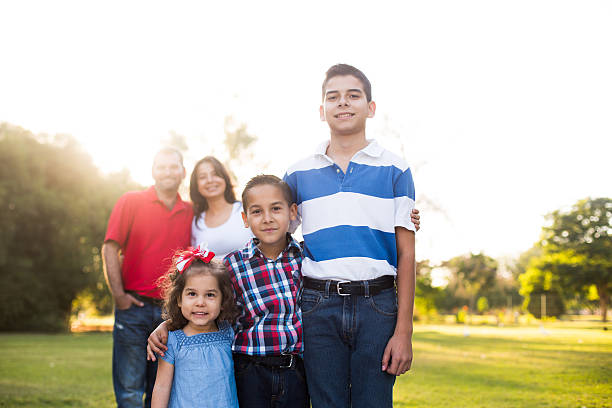 istock Three children standing with parents in background 545995352