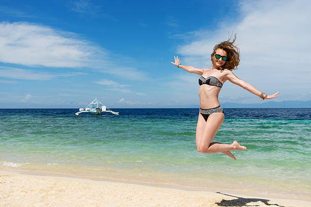 istock young girl is juming on the beach with white sand 546000398