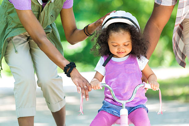 toddler daughter learning to ride a tricycle - family cheerful family with one child texas imagens e fotografias de stock