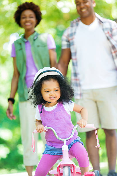 istock Happy toddler learning to ride a tricycle with her parents 546006000